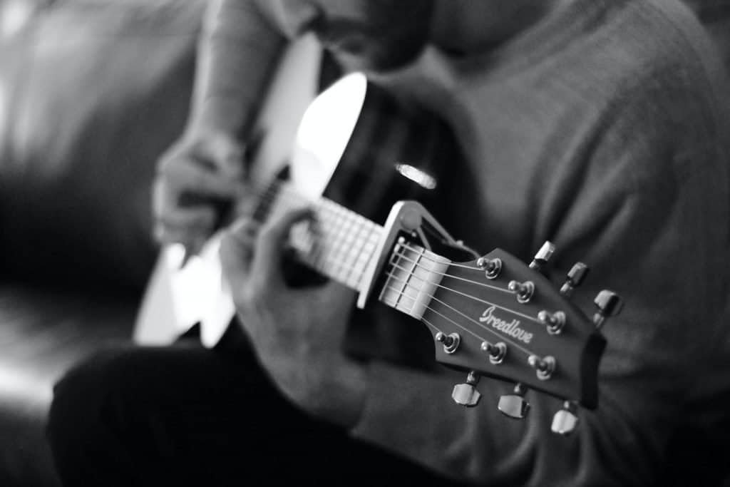 man playing guitar grayscale photo