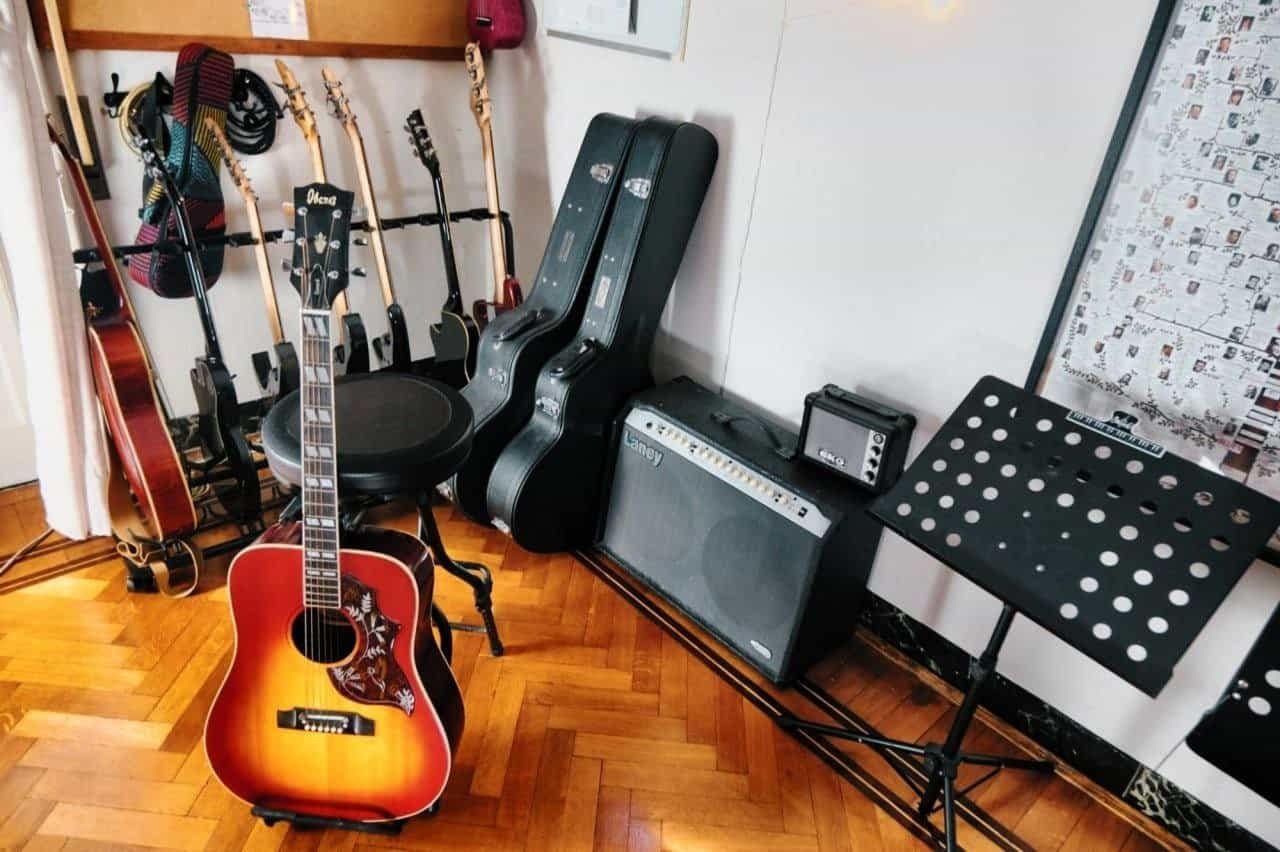Chitarra acustica, custodie e amplificatore nell'angolo strumenti dello studio